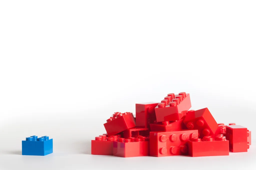 A Handful Of Bright Red LEGO® Bricks Next To A Single Blue LEGO® Brick